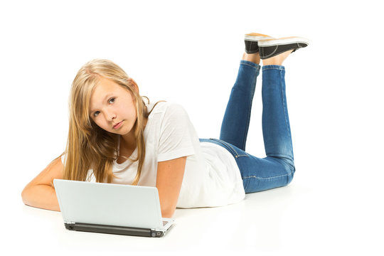 Young girl lying on the floor using laptop over white background