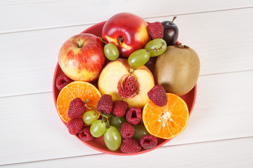 Fresh ripe fruits on plate lying on white boards