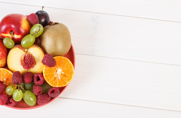 Fresh ripe fruits on plate lying on white boards, copy space for text