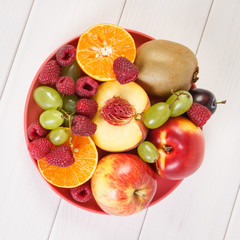 Fresh ripe fruits on plate lying on white boards
