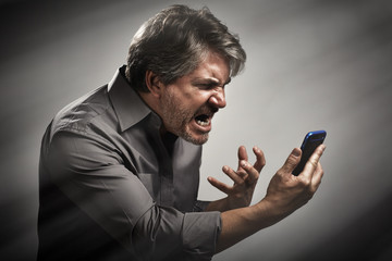 Angry screaming man with cell phone.