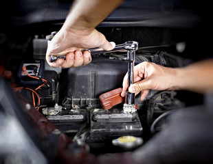 Hands of car mechanic with wrench in garage.