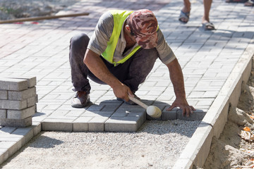 Worker puts sidewalk tile on the road