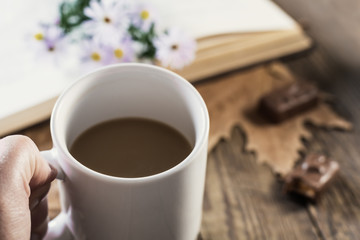 Chocolate candy and coffee mug in hand. Selective focus