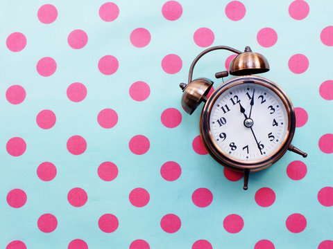 alarm clock on blue and pink polka dot background