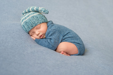 sleeping newborn baby in blue jumpsuit and hat