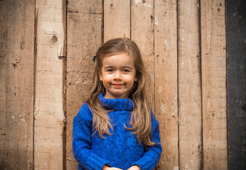 little girl in stylish clothes and a beautiful wooden background