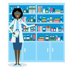 Pharmacist in drug store. Beautiful smiling african american woman in white standing near shelf with medication. Woman in glasses.