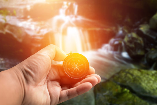 Compass in hand.Background waterfall