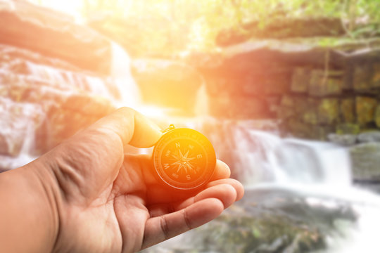 Compass in hand.Background waterfall