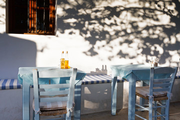 Restaurant tables under a tree with small bottles of olive oil.