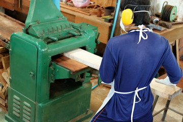 Top view,Worker is working with planing of wood machine.He is wearing safety equipment in factory