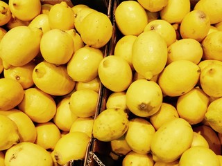 Pile of bright yellow lemons in fruit market, lemon background
