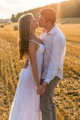 Young loving couple kissing in a field