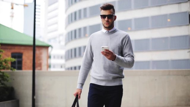 young man with sunglasses and bag walking in city