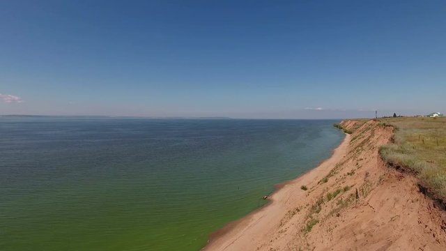 Aerial video of flying over the cliff and the sea.  Drone moving forward at high altitude. 4K Aerial stock footage shot at summer season time.
