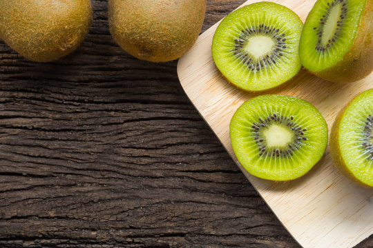 Kiwi fruit slices in a bowl on wooden background. Copy space