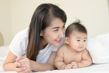 happy family.asian  mother playing with her baby in the bedroom.