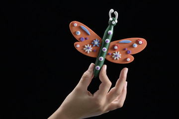 Mano de ni&ntilde;o sujeta juguete, hecho por &eacute;l, con forma de mariposa. Aislado en fondo negro.