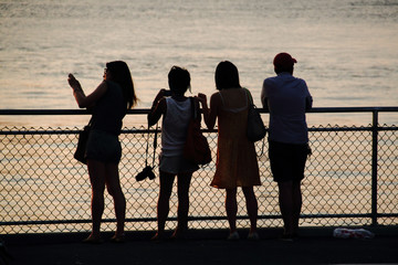 Four tourists taking pictures and looking at the East River on the Brooklyn side - 123310695