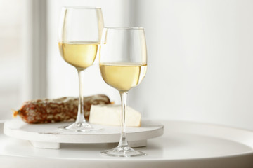 Glasses with white wine, cheese and wurst on a table