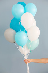 Woman holding many colorful balloons on grey background