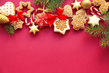 Tasty gingerbread cookies and Christmas decor on color background