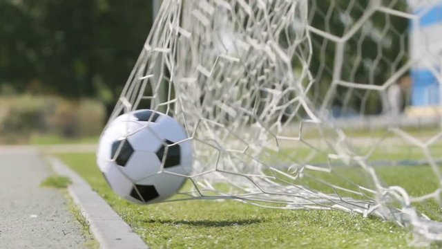SLOW MOTION: Soccer ball flies into a gate (close up)