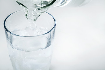 Pouring water on glass on white background