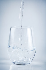 Filling a glass with water on white background