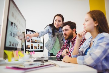 Businesswoman showing computer screen to coworkers