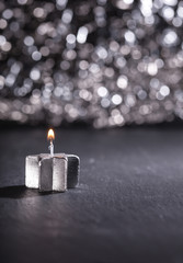 Silbere Kerze brennt vor glitzerndem Bokeh Hintergrund