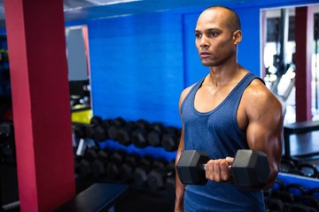 Determined man exercising with dumbbells