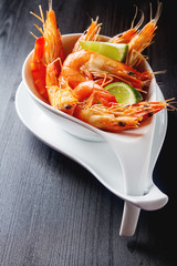 Fresh raw shrimps, lime in a bowl on a wooden table. Eating seaf