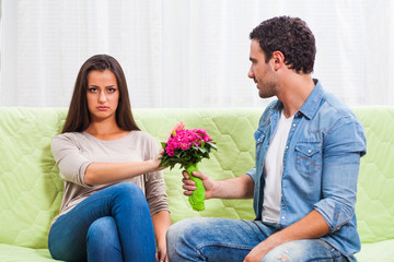 Young couple is sitting at sofa at home. Woman is angry.