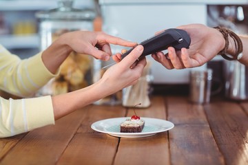 Smiling woman entering pin number into machine at counter