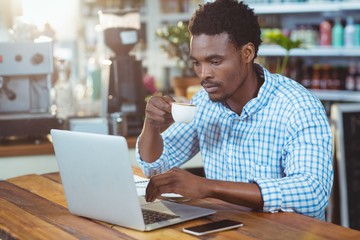 Man using a laptop while having cup of coffee
