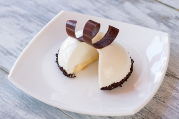Sliced dessert on plate. Sweet dish on wooden surface. Delicious vanilla mousse cake. Recipe from experienced pastry chef.