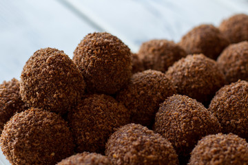 Sweets of dark color. Desserts covered in crumbs. Tasty chocolate rum balls. Biscuit is the main ingredient.