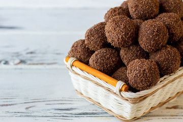 Dark colored sweets with crumbs. Desserts in a basket. Special recipe of chocolate balls. Mixture of cocoa and biscuits.