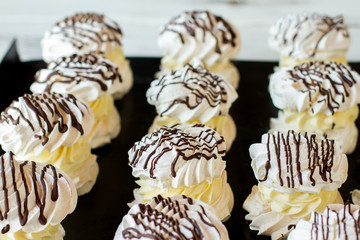 Rows of meringues. Desserts on dark surface. Sweet treats in french cafe. Product from eggs and sugar.