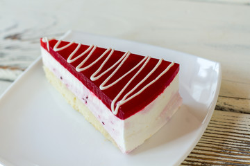 Piece of cake on plate. Dessert with red jelly. Mousse and dough. Flavor of currant.
