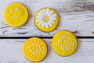 Top view of iced cookies. Round biscuits on wooden background. Flower and smiling sun. Art starts...