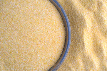 Corn meal in a bowl surrounded by more grain top close view.