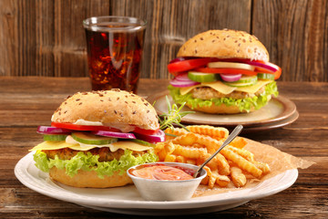 Fresh tasty burger with fries and drink on wooden table
