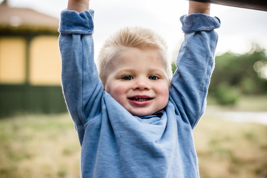 Boy hanging on bars in playground - Powered by Adobe
