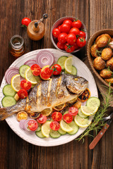 Grilled fish with roasted potatoes and vegetables on the plate