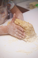 Vintage tonned photo with kid kneading the dough. Child helps to cook tasty cookies