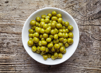 White bowl of canned green peas, from above
