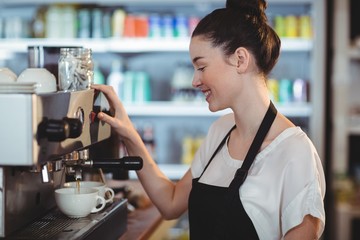 Smiling waitress making cup of coffee